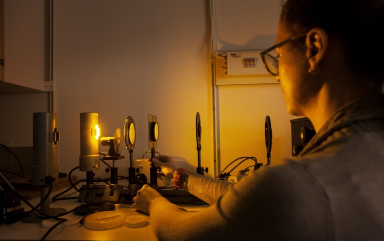 Laboration med ljus genom filter. En student håller på att ställa upp filtrerna