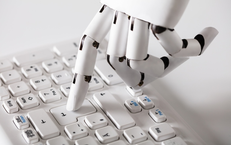 Robothand som trycker på "enter" på ett tangentbord.