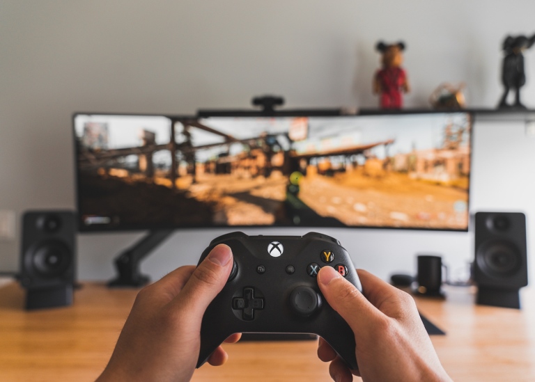 Genre photo: Person holding a control and playing a digital game, the photo illustrates research.