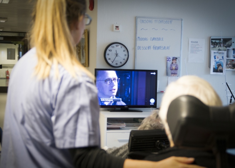 Bild från ett äldreboende med en kvinnlig sköterska bredvid en patient