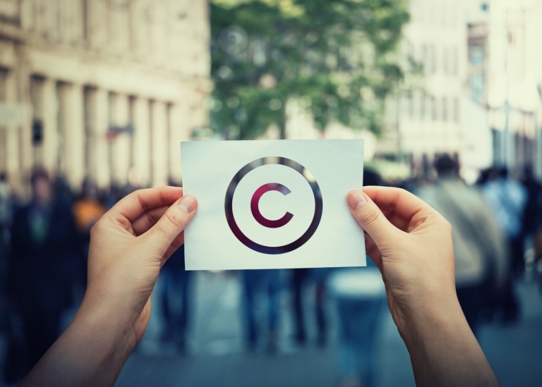 Händer som håller upp skylt med copyright-tecken på