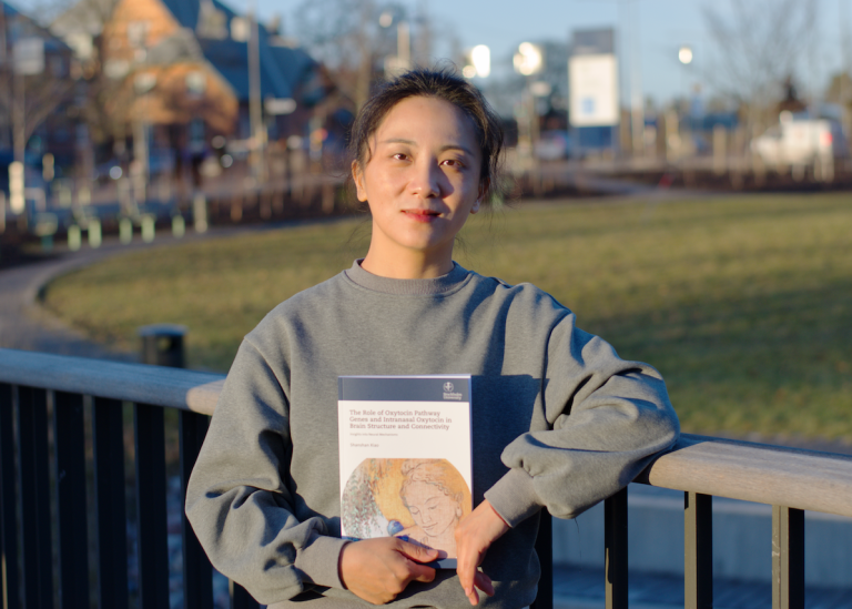 Shanshan Xiao, standing on a bridge outside Campus Albano, holding the thesis.
