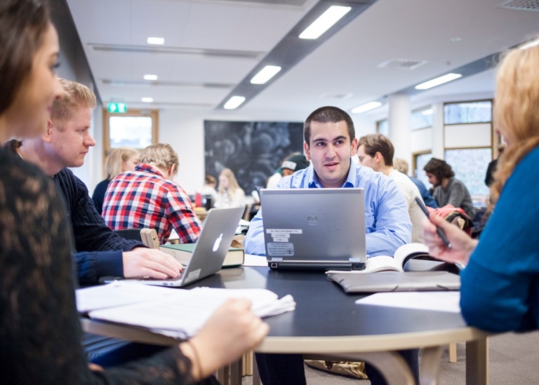 Students writing and talking. Photo: Niklas Björling