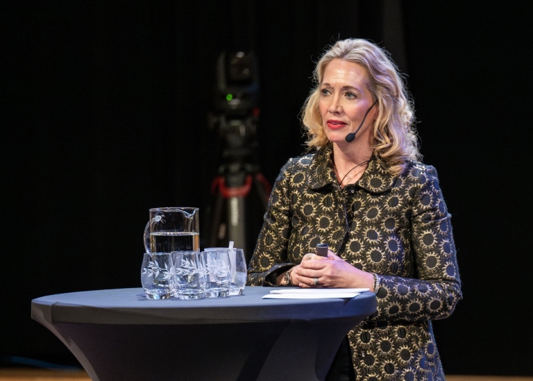 Mia står på scenen vid ett ståbord