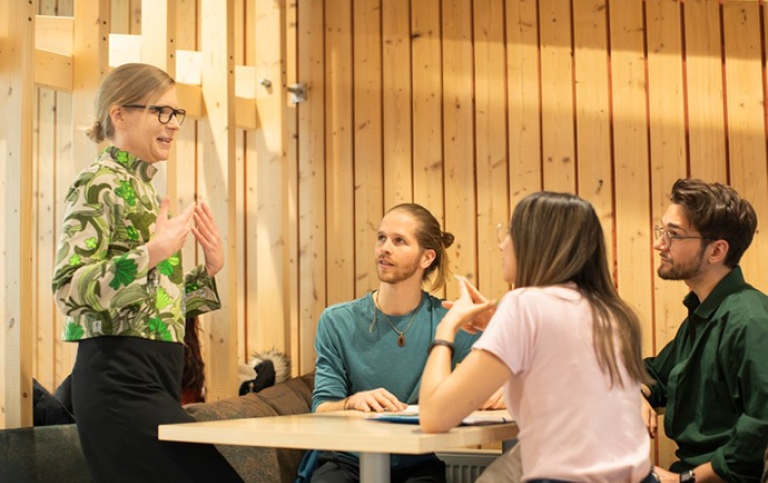Lärare pratar med tre studenter.