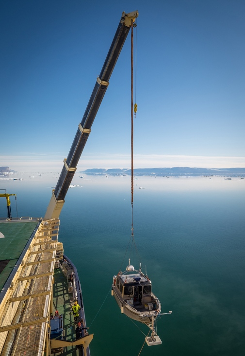 Launching of small research vessel from icebreaker Oden, calm sea with some icebergs on a distance