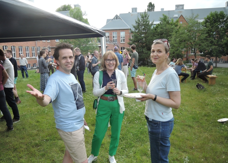 Sommarfest utomhus, tre personer i förgrunden.