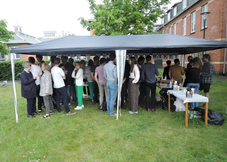 Sommarfest utomhus, alla inklämda under partytältet.