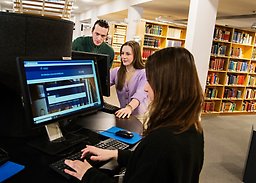 Studenter står vid datorer i Universitetsbiblioteket.