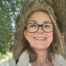 En leende blond kvinna framför ett träd