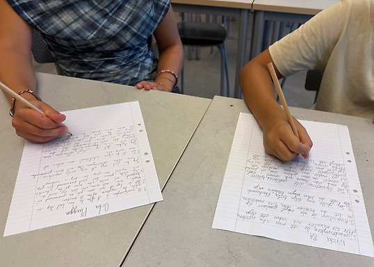 Elever skriver på papper för hand