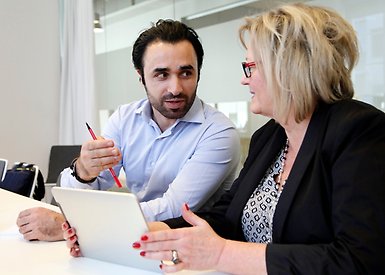 Kvinna och man samtalar vid bord med sursplatta
