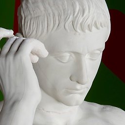 Antik staty av marmor, där man ser en hand och ett huvud.