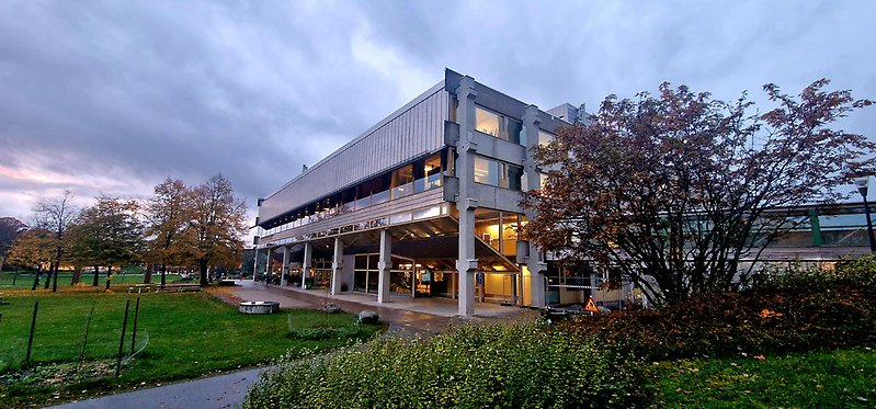 Arrheniuslaboratoriet, grå molnig himmerl, gröna gräsmattor, träd i höstfärger.