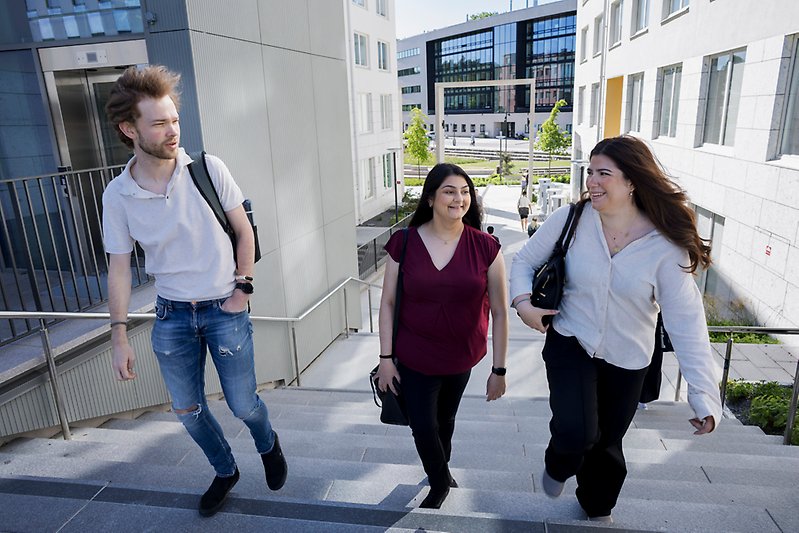 En manlig student och två kvinnliga studenter i en trappa på Campus Albano, Stockholms universitet.