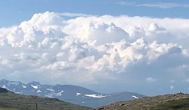 Blå himmel, vita moln, berg.