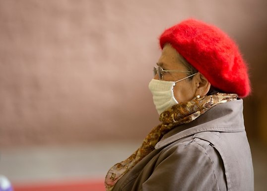 Äldre kvinna med basker och kirurgisk mask