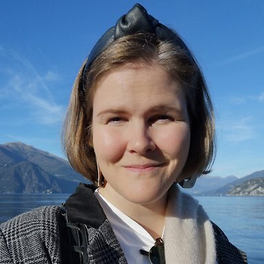 Sanni Kuikka står vid en sjö med berg i bakgrunden