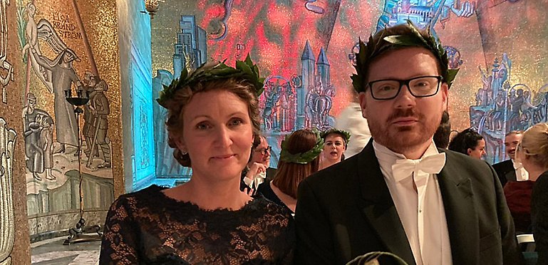 Jessica Douglah och Johan Christensson i lagerkransar sitter ned på banketten i Gyllene salen.