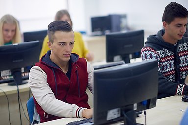 People sitting by tables with screens.