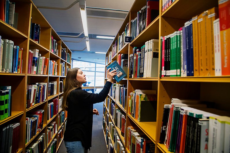 Kvinna tar ned en bok från en hylla