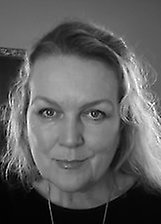 Svartvitt porträtt av Malin Roitman som tittar rakt mot kameran. Ansiktet syns i närbild mot en mörk bakgrund.