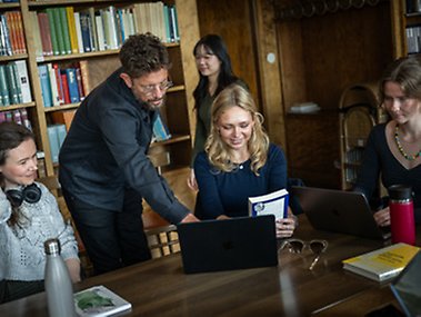 Lärare instruerar student vid dator.