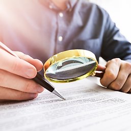 person holding a pen and a magnifying glass