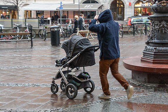 Father pushing a stroller running from rain.