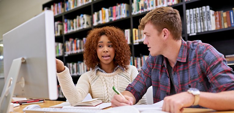 Två studenter diskuterar sitt arbete.
