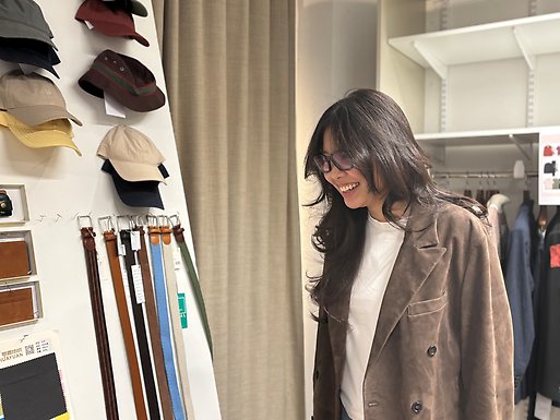 Person standing in front of a screen with neatly arranged garments.