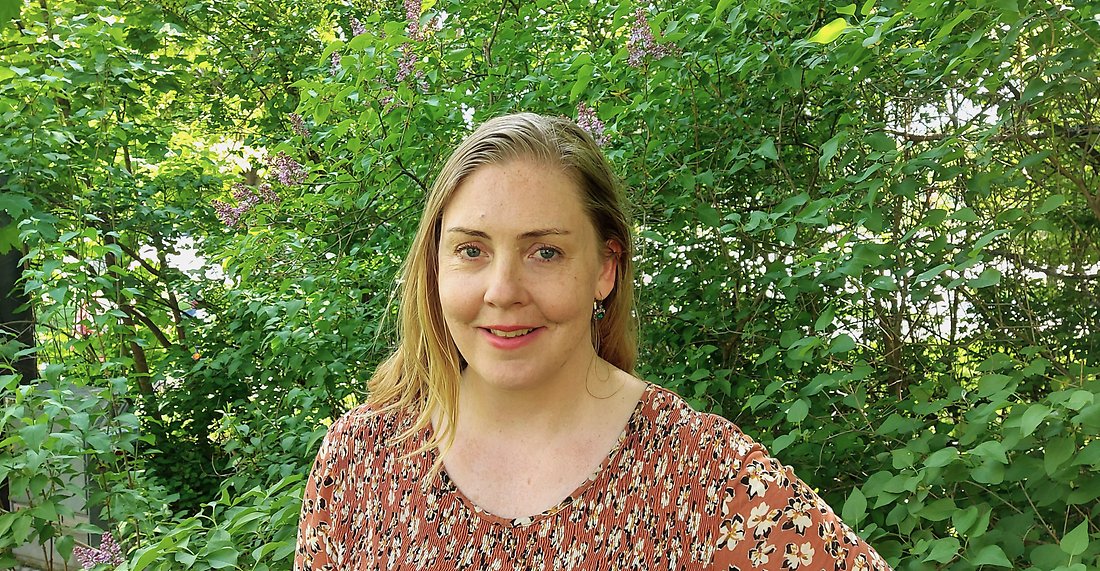 Caroline framför syrenhäck.