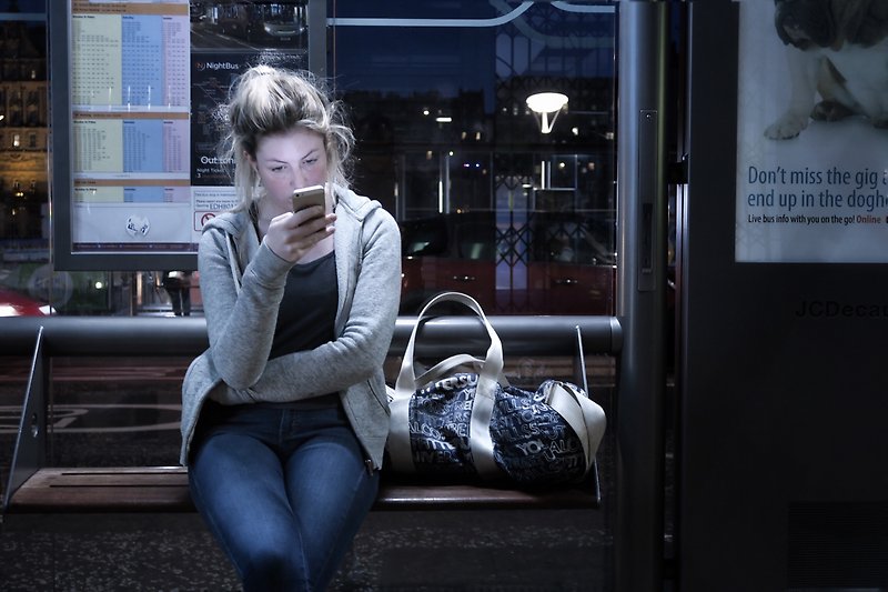 Kvinna tittar på sin mobiltelefon,