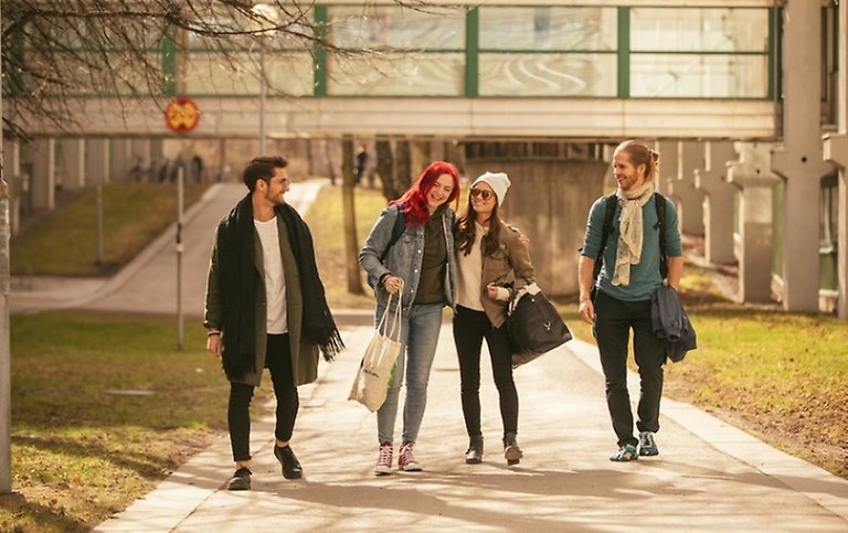Fyra studenter går på campusområdet.