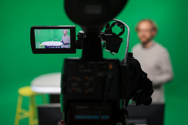 Bild från en studio. Man kan se en programledare genom kameralinsen. 