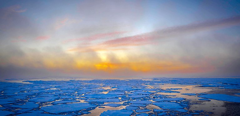 Light blue sky with grey-whie, red and orange clouds, water and bright blue ice floes.