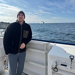 Léon Chafik standing by the railing on deck on RV Skagerak. Water and a ship in the background.