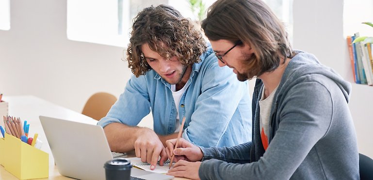 Två manliga studenter diskuterar sitt arbete.