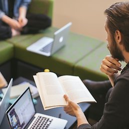 En student med ryggen mot kameran läser en bok.