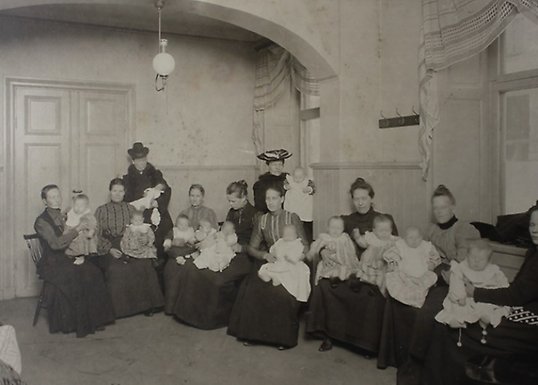Mödrar och barn i väntrummet hos Föreningen Stockholms mjölkdroppar, tidigt 1900-tal..