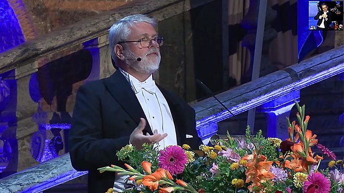 Jan Pedersen i frack står vid podium smyckat av blommor.