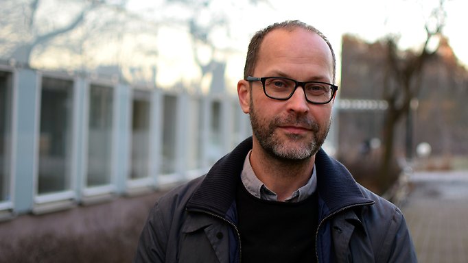 Porträttfoto på Magnus Bygren med campusbyggnader i bakgrunden.