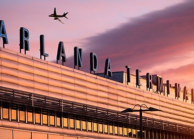 Arlanda sign on building, sunset sky and an airplane flying.