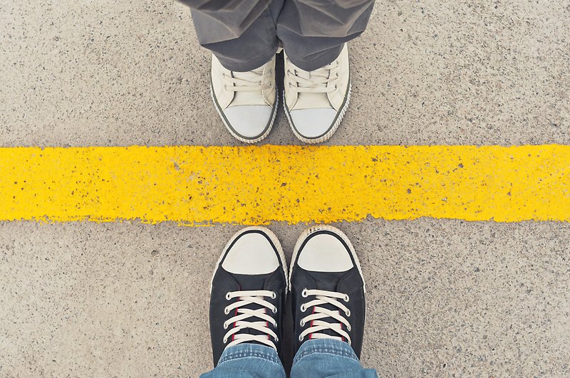 Sneakers from above with a yellow line in between symbolizing a boarder.