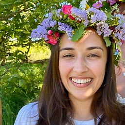 Sophia outside in a green environment, wearing a midsummer wreath on her head.