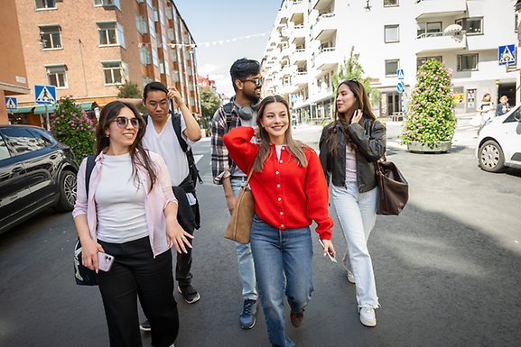 Three women and two men are walking on a street.