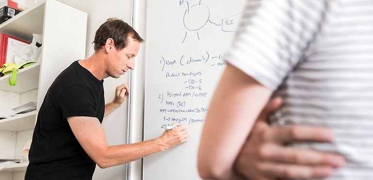 En man skriver på en whiteboard.