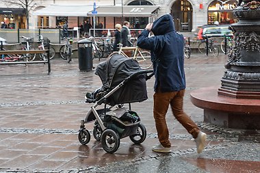 Father pushing a stroller running from rain.
