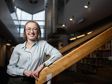 Sofia Lodén står på en trappa i ett bibliotek.