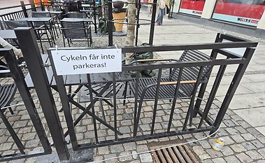 Staket runt café, men skylt på staketet med texten Cykeln får inte parkeras!.